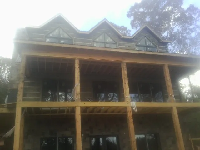 Dormers and porch framing on a large log home under construction — Roof Coating work by our crew in Pilot Hill