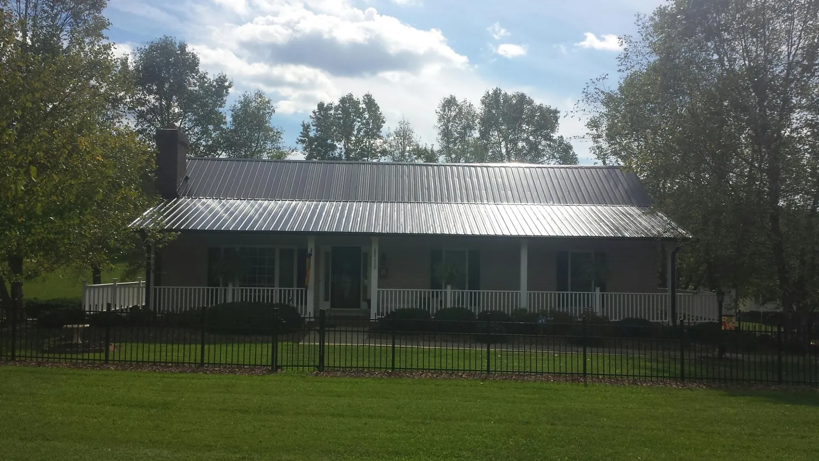 Gray metal roof on a brick ranch with a full width front porch — Gutter Guard Installation work by our crew in Pilot Hill