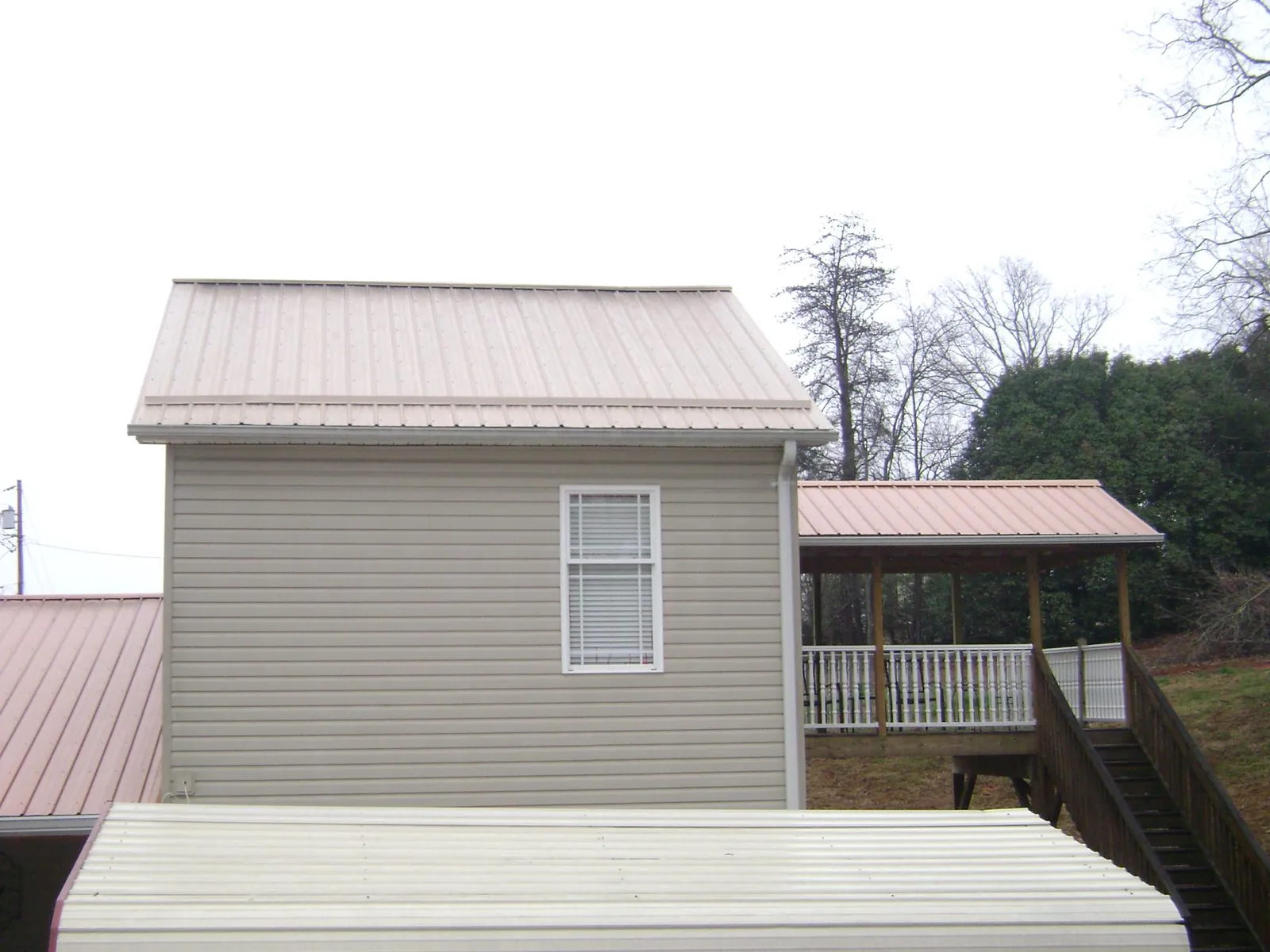 Tan metal roofs on a two story addition and attached porch, from a Roof Replacement job in Pilot Hill